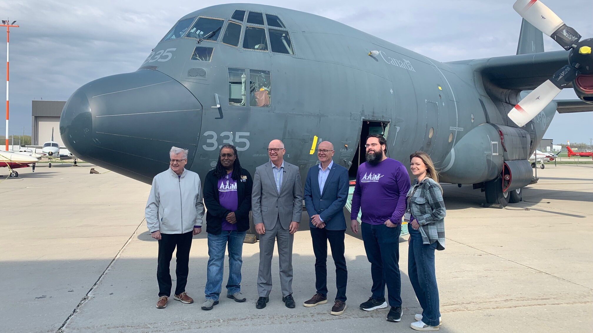 Six people stand in front of a big plane.