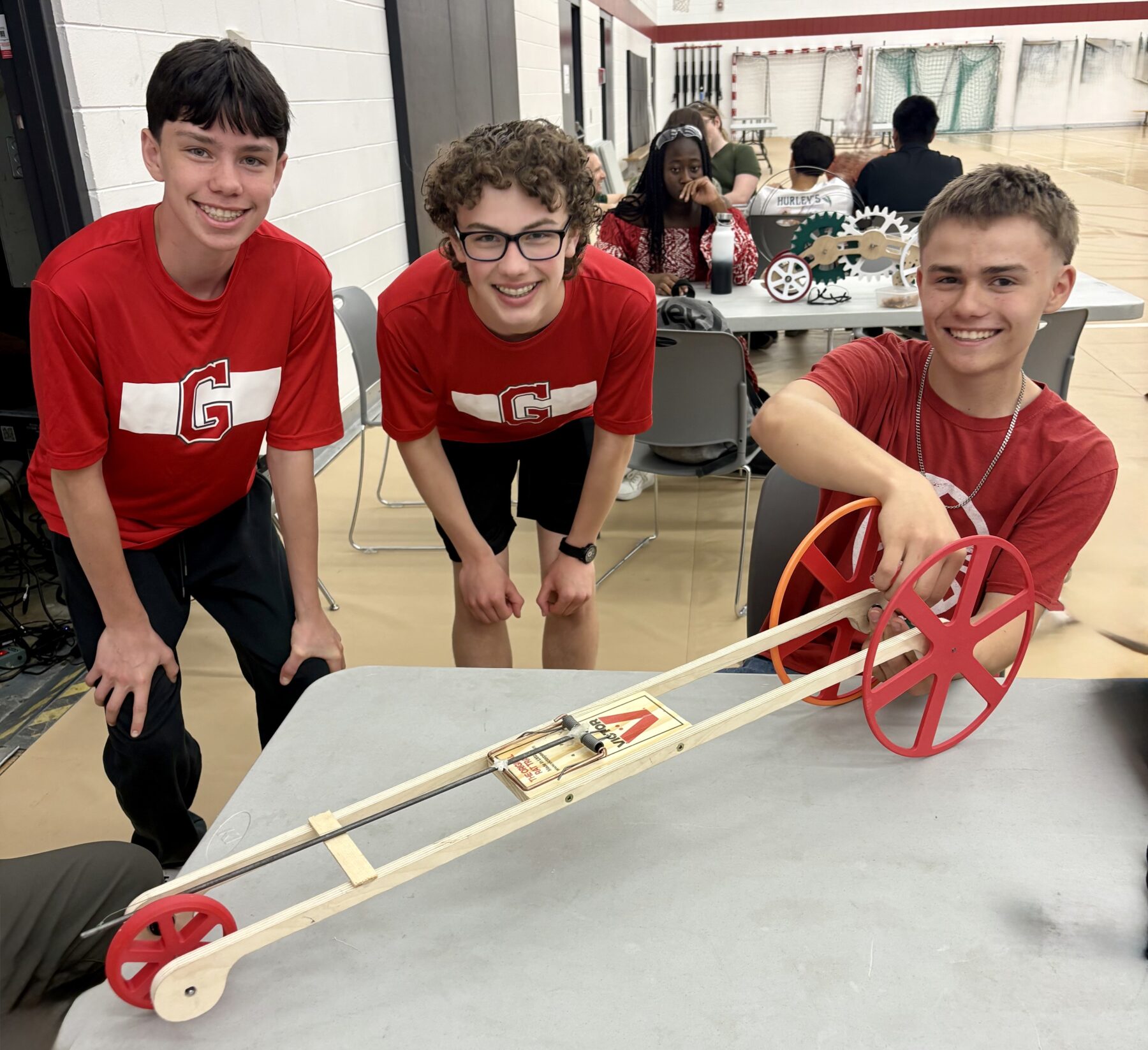 3 students displaying a model car