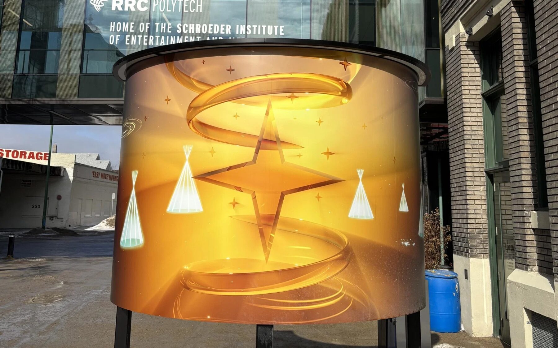 A large bright cylinder featuring stars and swirls stands outside RRC Polytech's Exchange District Campus. 