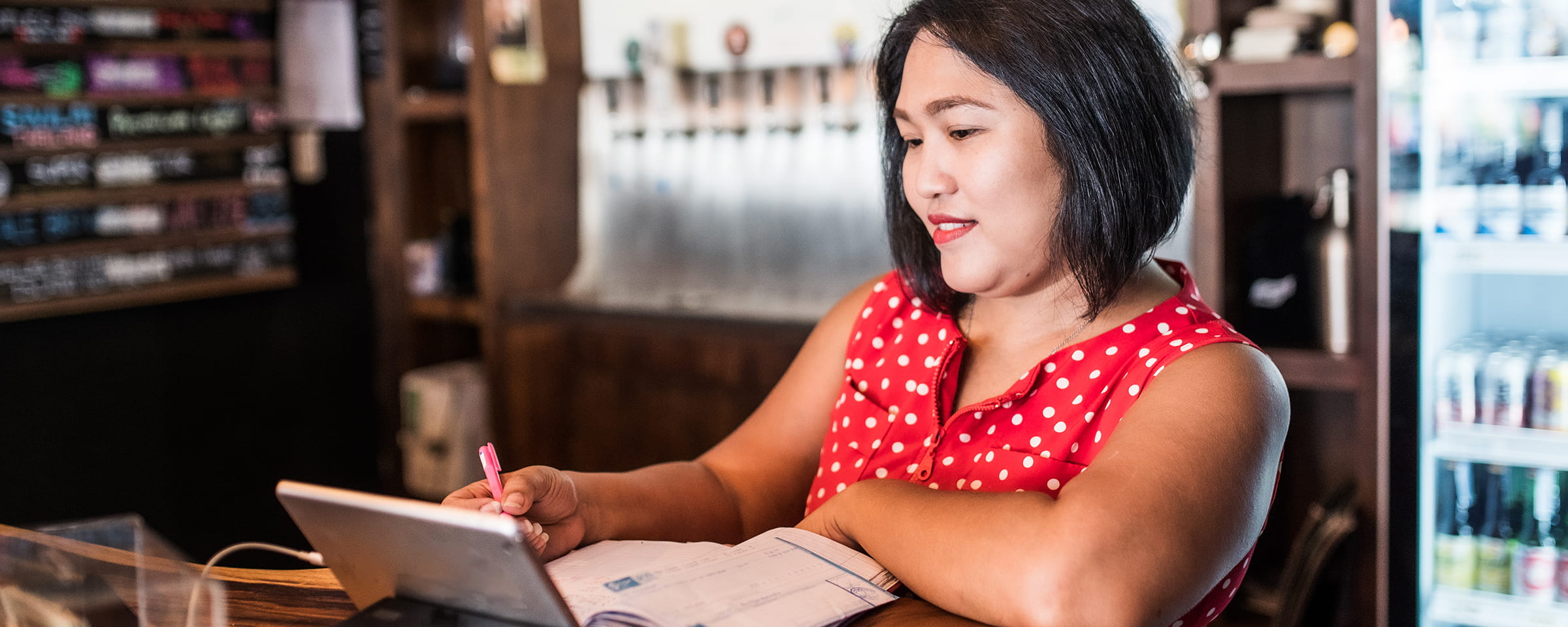 Woman taking notes while looking at a tablet