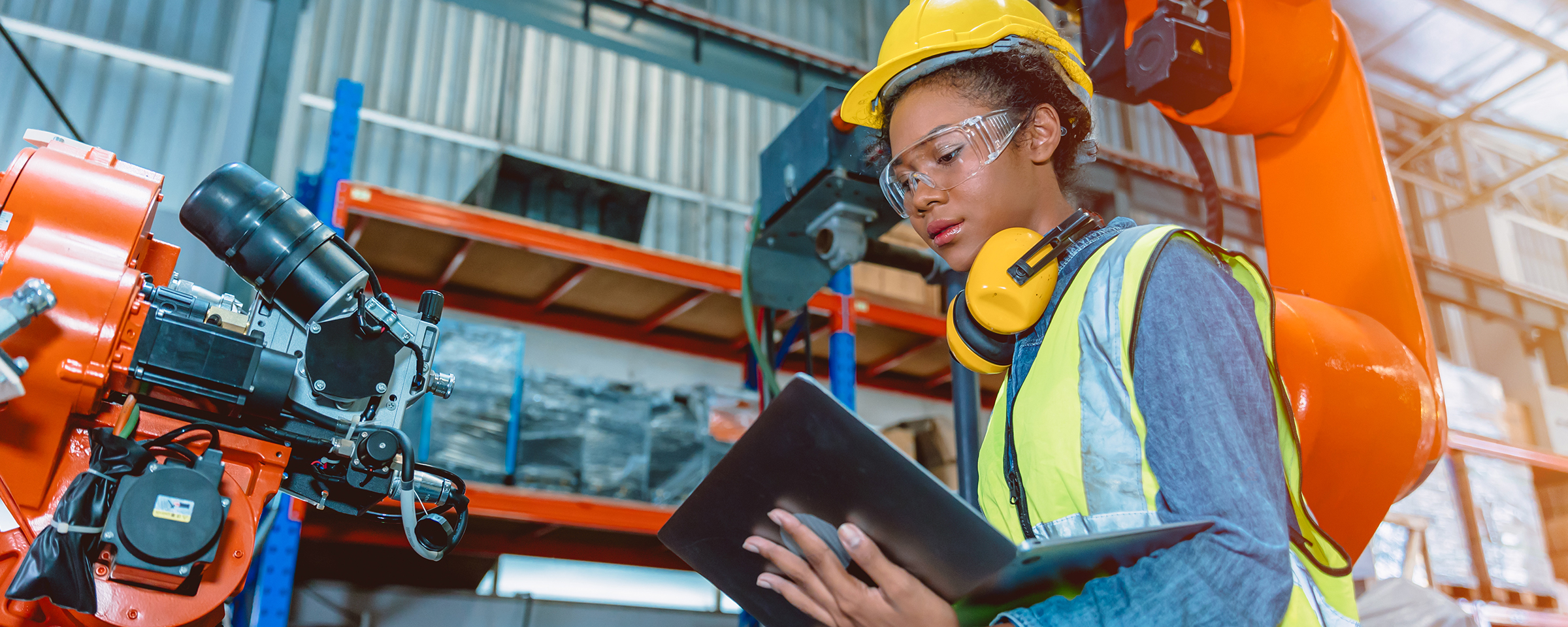 Woman wearing hardhat in factory with a laptop