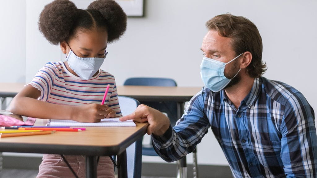 Male educational assistant working with young female student