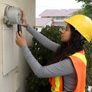 Female energy advisor takes outdoor meter reading.