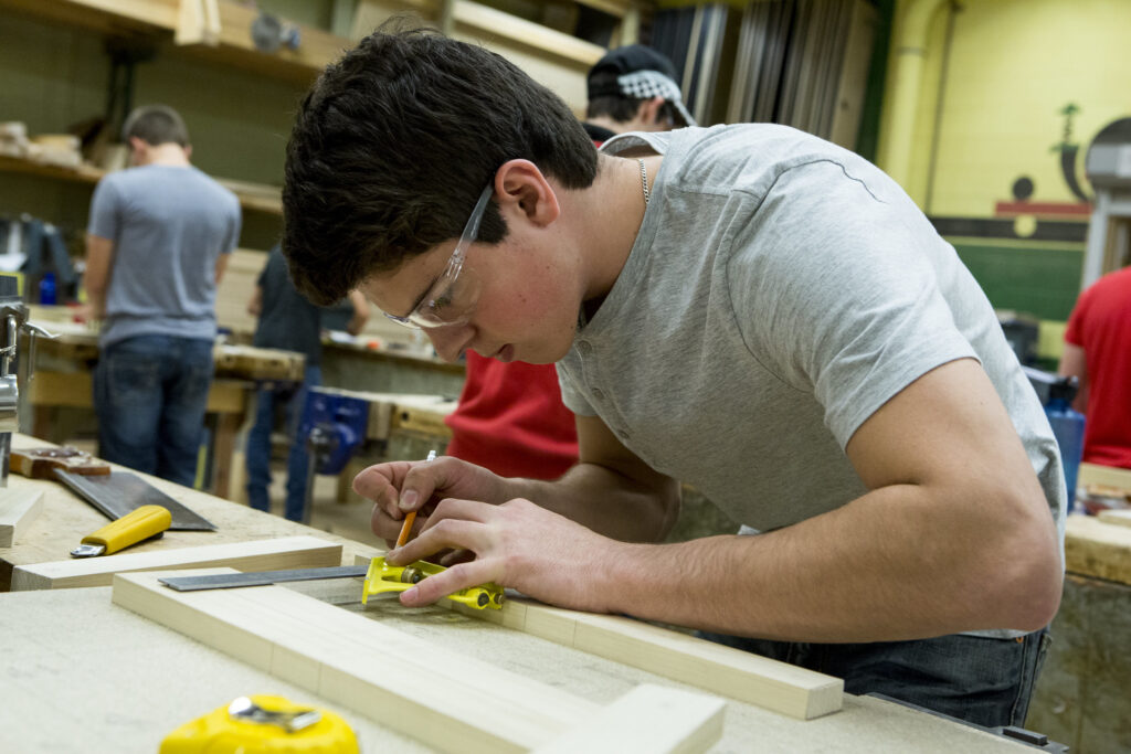 Male student works on carpentry project in woodworking lab