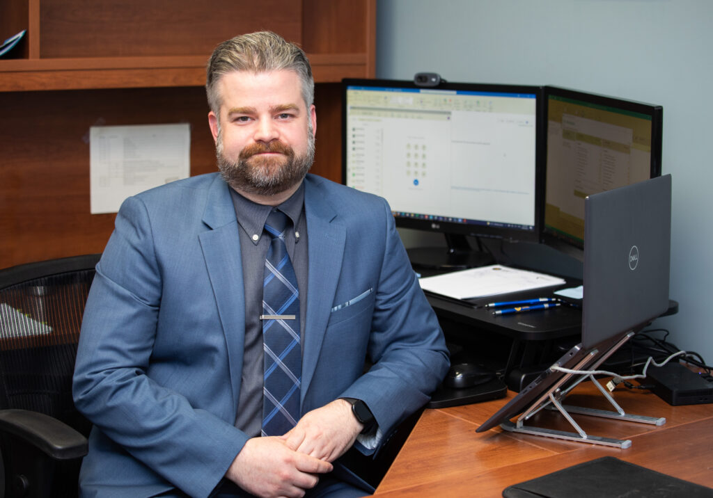 Business Administration grad Paul Dorey, seated in office