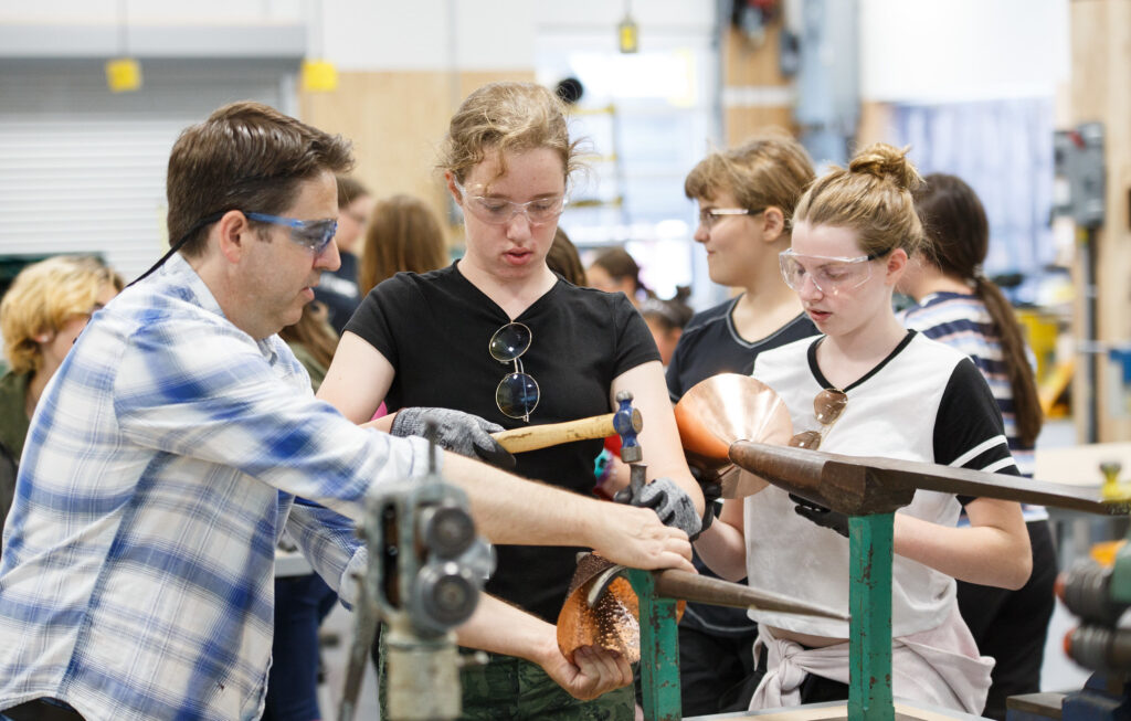 Teenage girl hammers metal while taking part in Girls Exploring Trades and Technology camp at RRC Polytech