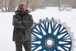 Cascade Manufacturing's Matt Waldmer, standing next to all-steel bolted wheel for irrigation systems