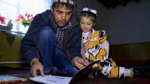 Man in Tajikistan reading to young girl