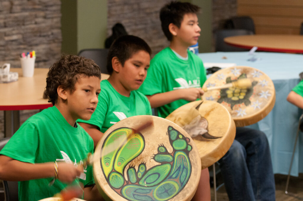 Three Indigenous boys drumming as part of RRC Polytech summer youth camps
