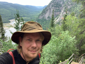 Photo of Josef Neufeld on hiking trail, with mountains in background