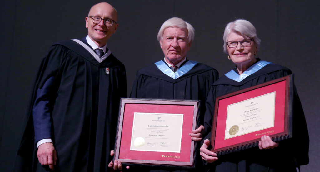 RRC President Fred Meier presenting honorary degree to Walter and Maria Schroeder at Fall 2022 convocation ceremony.