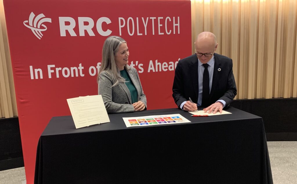RRC Polytech President Fred Meier signing the SDG Accord at table.