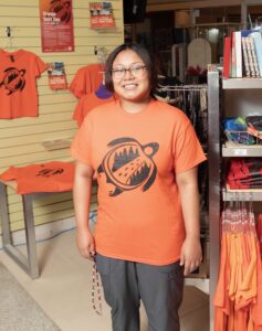 Portrait of RRC Polytech Nursing student Dasia Chatkana, wearing the t-shirt she designed for Orange Shirt Day.
