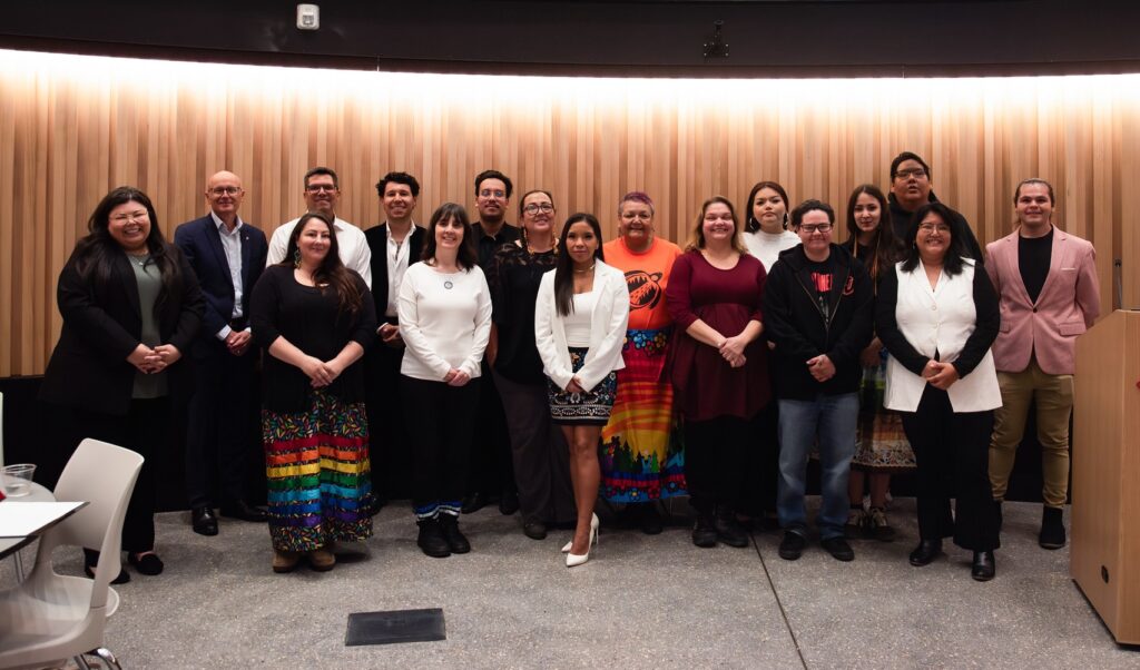 Group of entrepreneurs and students assembled in a row in RRC Polytech's Roundhouse Auditorium.