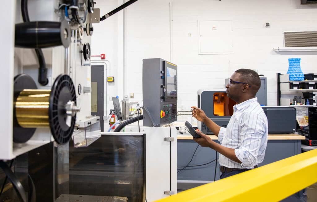 Male researcher programs equipment in RRC Polytech's Technology Access Centre for Aerospace and Manufacturing