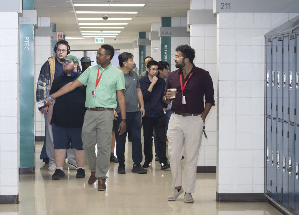 Men with RRC Polytech lanyards lead students down a hallway at South Winnipeg Campus.