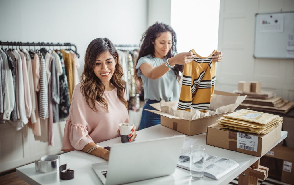 Women accepting new orders online and packing merchandise for customer