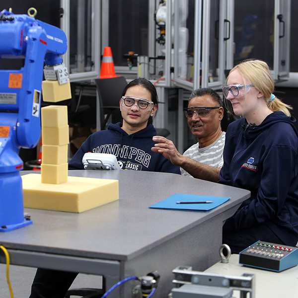Students operating a robotic arm
