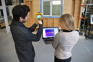 To professionals scanning wall with Fluke thermal scanner to test if it meets green building and energy efficient requirements
