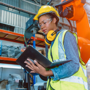 Woman wearing construction gear on a laptop in a factory