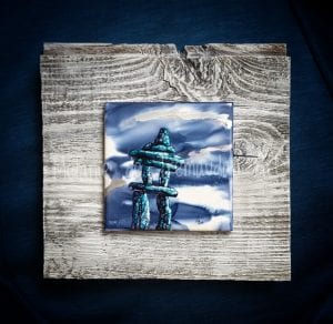 Painting in blues and white of an inuksuk mounted on wood