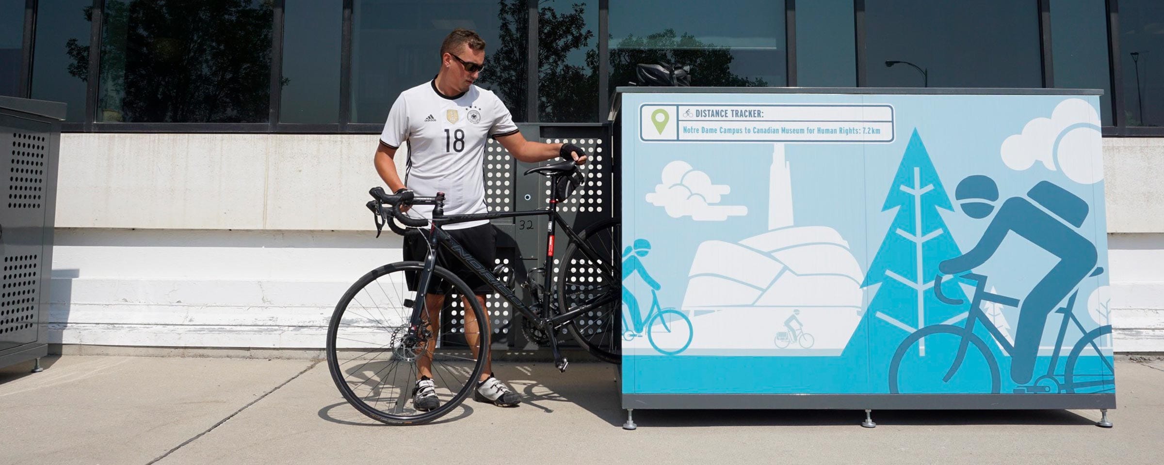 A cyclist putting their bike into a bike locker at NDC