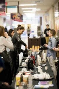 A young woman pours a sample of fair trade coffee at the fair trade coffee booth in the halls of the Notre Dame Campus.