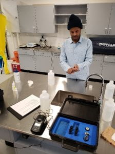 A student in a dress shirt and torque works in a lab testing water quality samples.