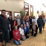 20 Staff and Students wearing green ribbons posing for a photo in the hallway outside the student lounge