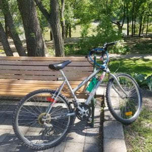 A bike learning against a bench in a park