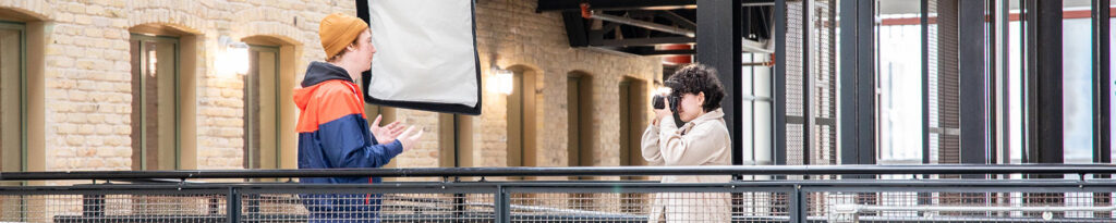 A student taking a photo of another student with a DSLR camera