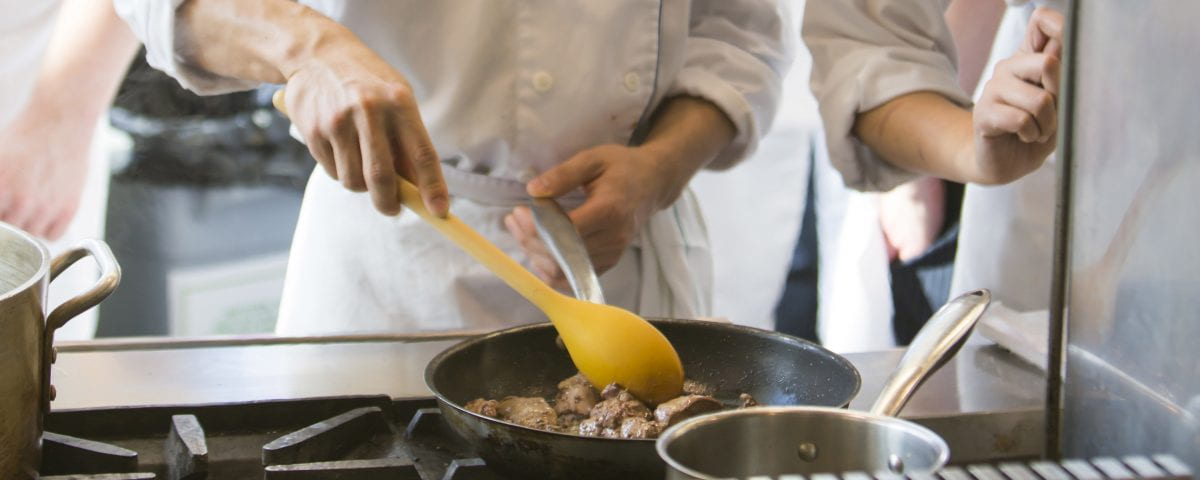 A student's hands are seen cooking in the Culinary Arts Kitchen