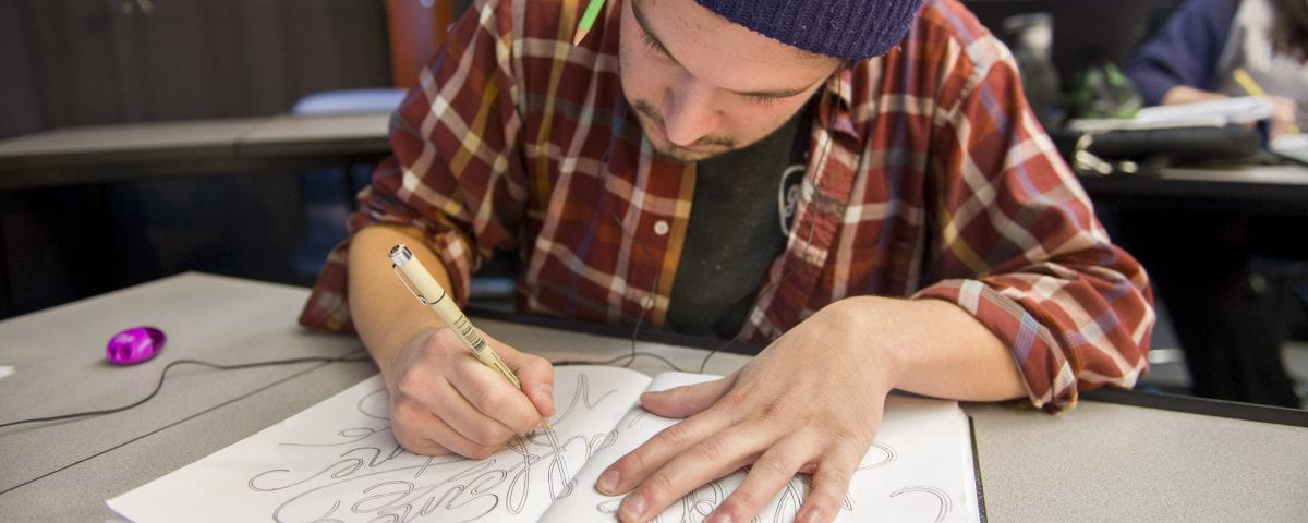 A graphic design student is pictured drawing