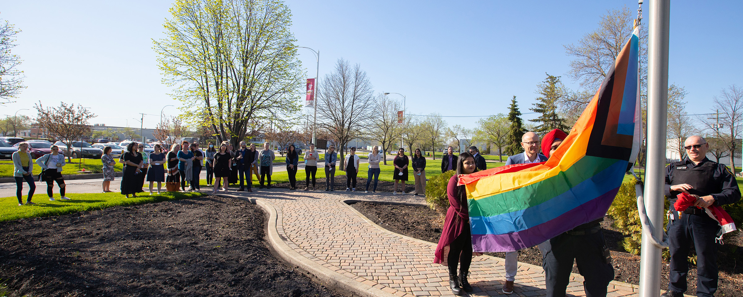 RRC Polytech gather around the Notre Dame Campus as Fred Meier, Sukhjot, and Jhavani hoist the Pride flag