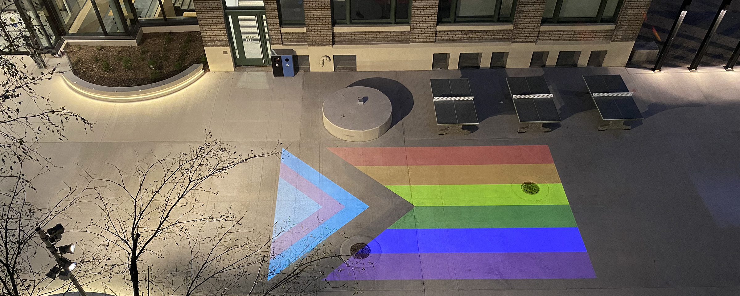 Progress Pride flag projection on the grounds of Elgin Avenue Plaza