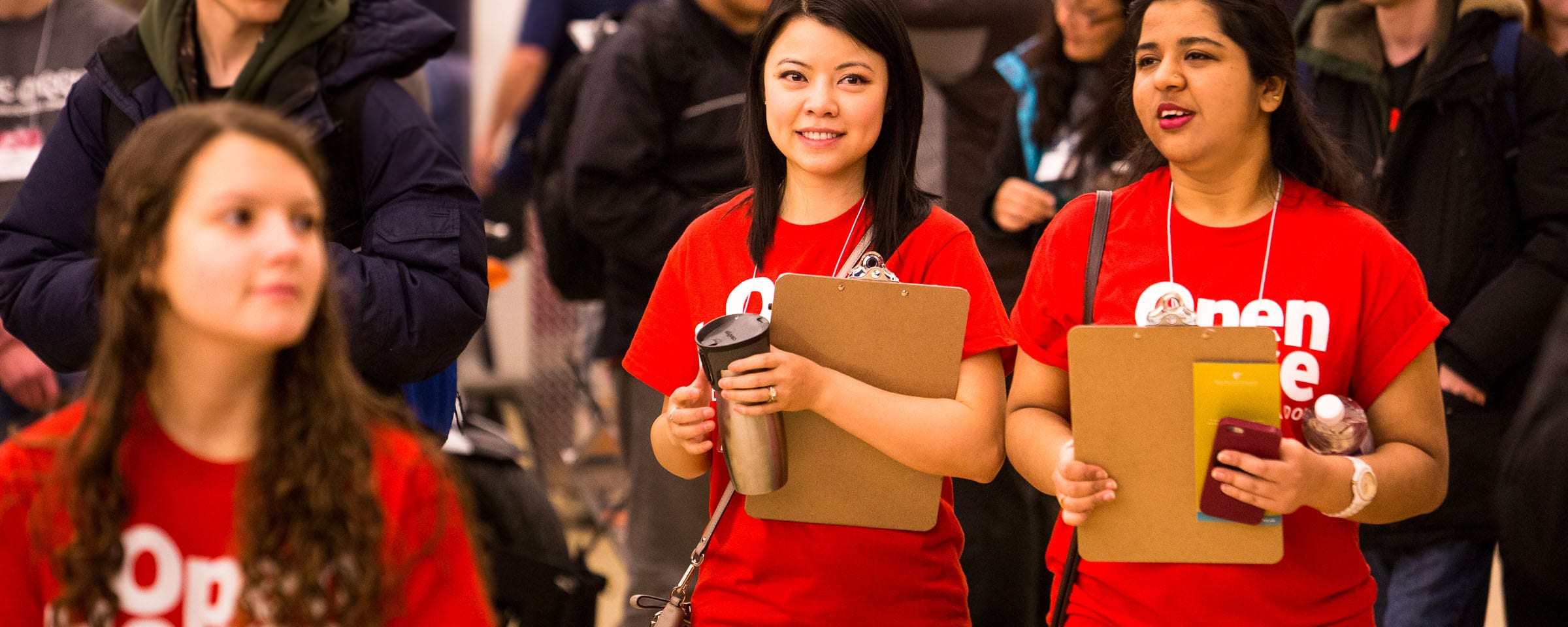 Group of students going through an open house, and two students in red shirts guiding the rest of the students. 