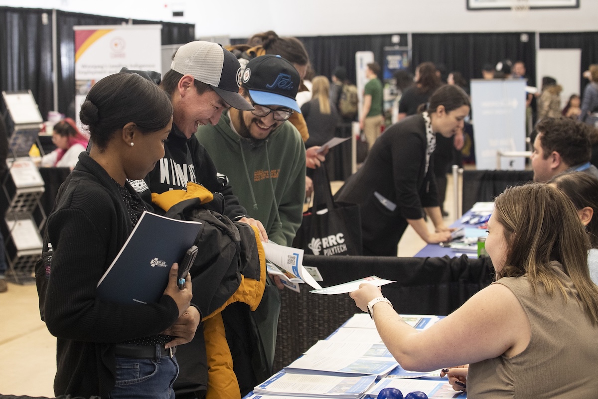 group of students interacting with rrc polytech staff at a booth