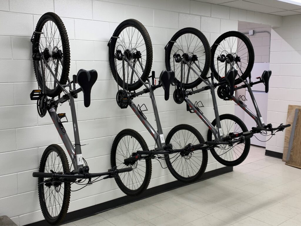 Four black bikes hanging on wall brackets.