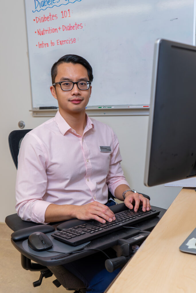 Registered dietician, Hao-Yi sitting at a desk with keyboard and monitor.