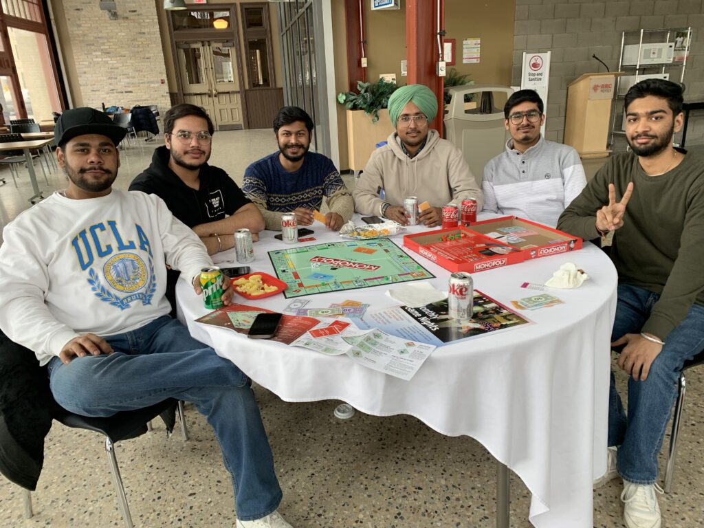 Six international students sitting around a table playing Monoply.
