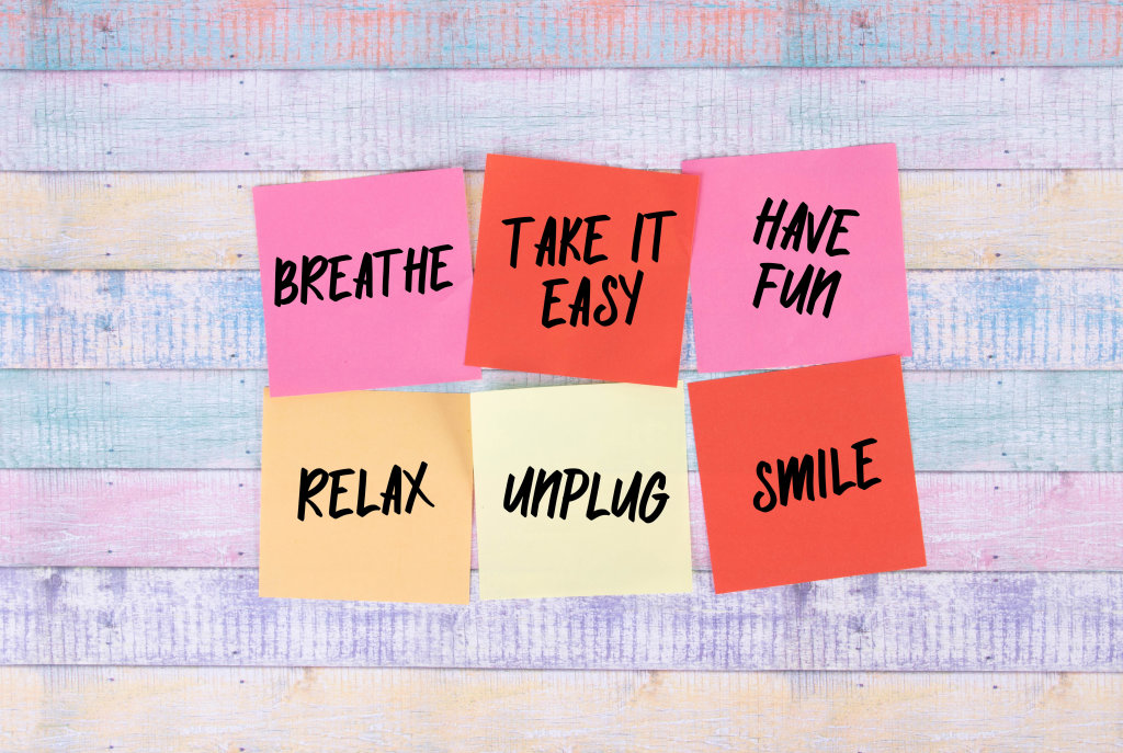 6 pink, orange and yellow sticky notes that say breathe, take it easy, have fun, relax, unplug, smile. 