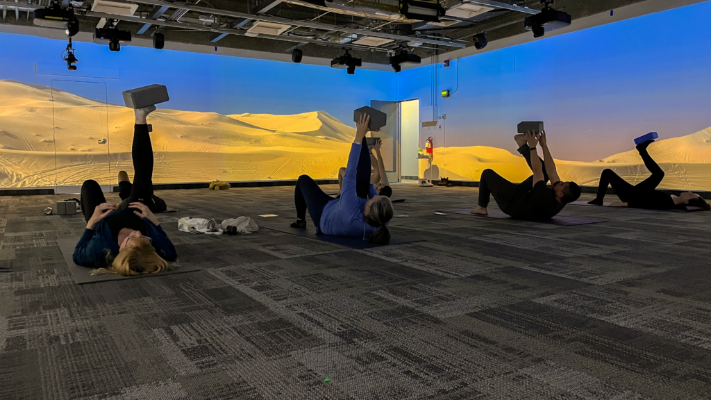 Several students on their backs holding a yoga pose.