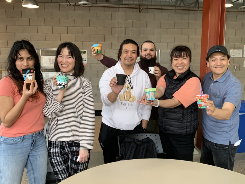 group of painters showing off their painted flower pots.