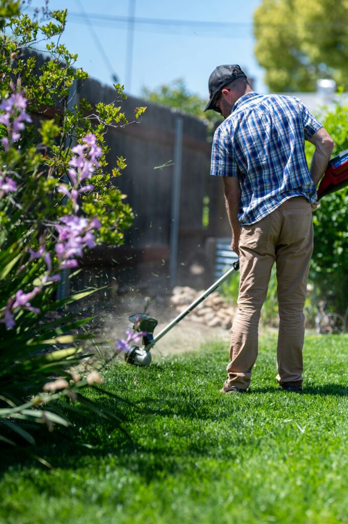 Person in using a weed trimming machine in a garden.