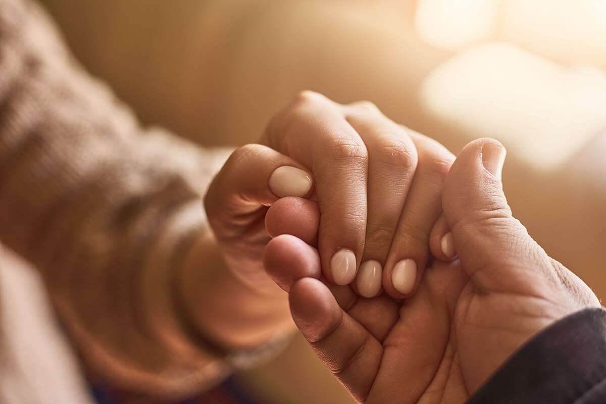 A close up of someone holding another person's hand in support.