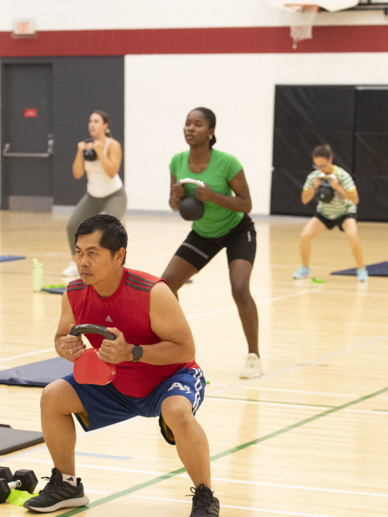 Four people lifting kettle bell weights in a fitness class.