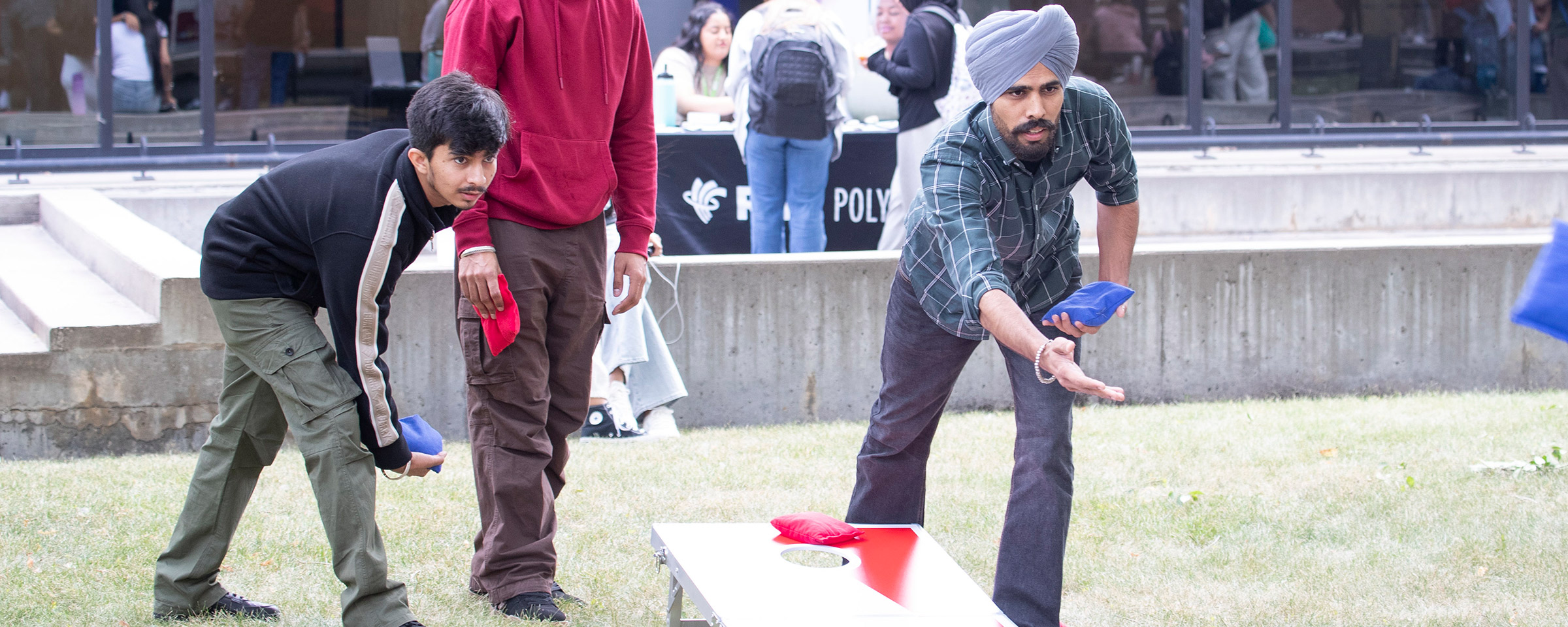 People playing bag toss outdoors