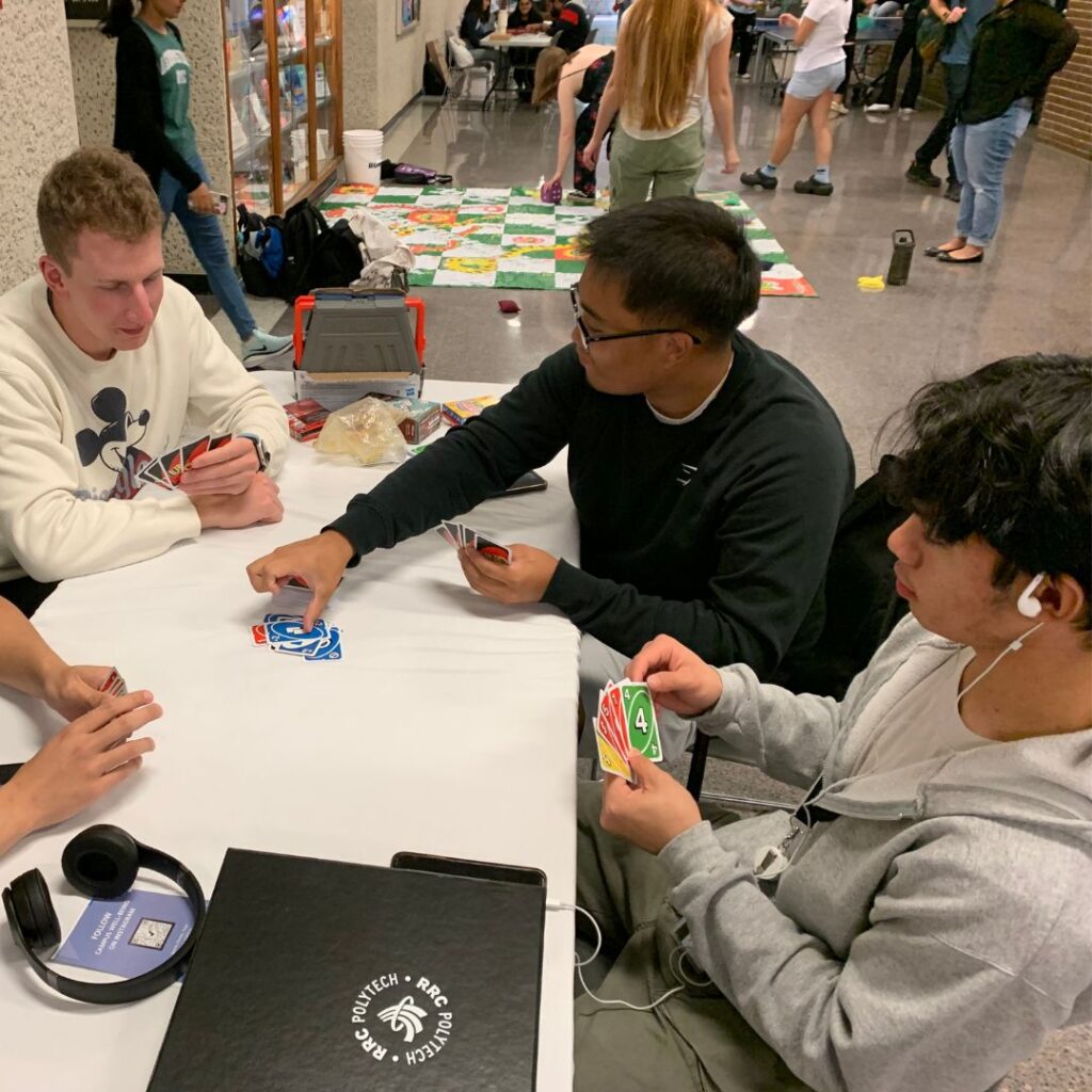 Group of students playing uno around a table. 