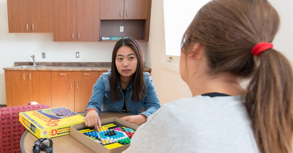 Two students in conversation while playing a board game.