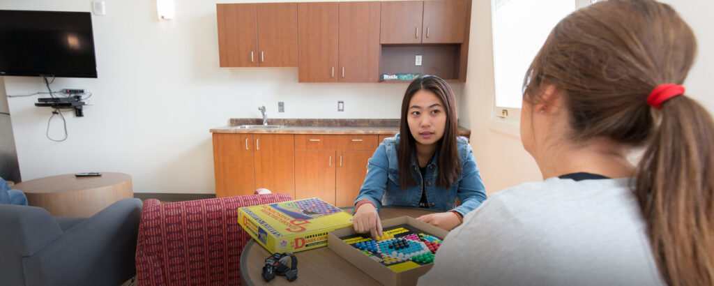 two students having a conversation while playing a board game